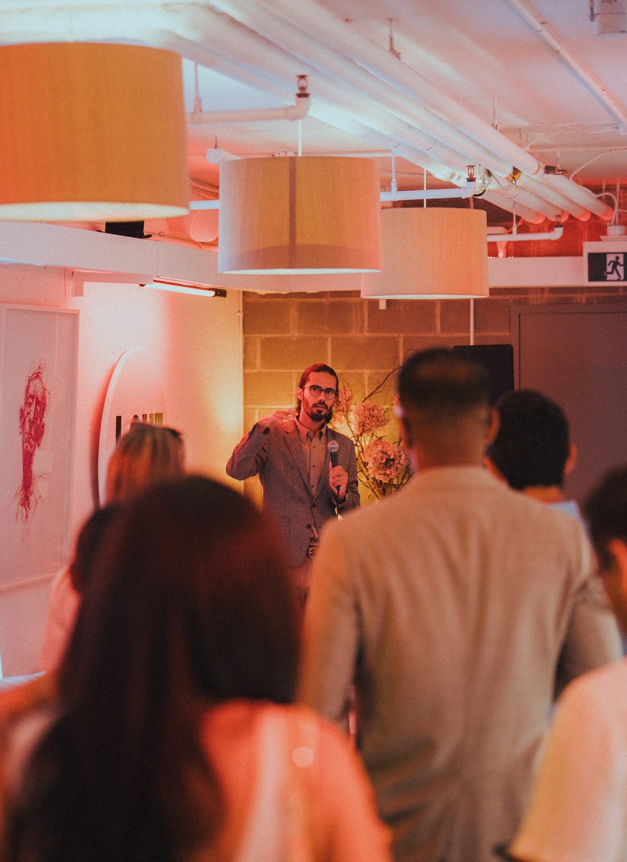 A speaker addressing the room under warm light at the Founder Feast Main Event on July 30