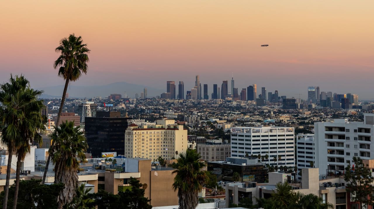 Downtown Los Angeles skyline at sunset seen past Hollywood palm trees