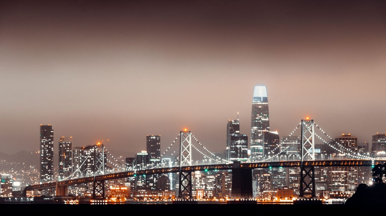 San Francisco skyline lit up at night behind the Bay Bridge