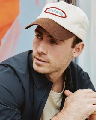 Connor Emeny in a cream and brown cap and a navy shirt, looking off to the side
