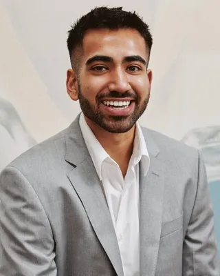 Vansh Sobti, smiling, in a light grey suit jacket and open white shirt