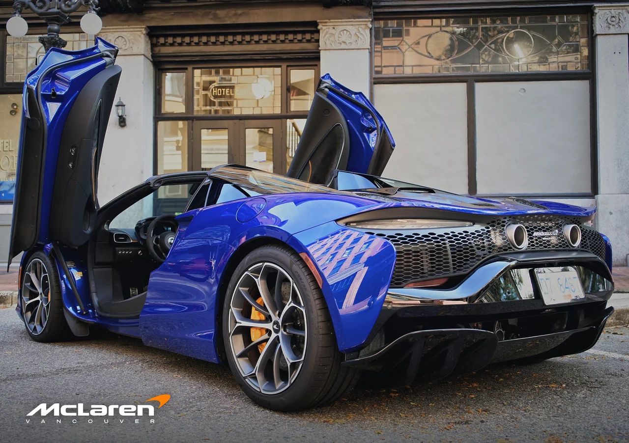 The rear three-quarter of the Artura Spider, doors raised.