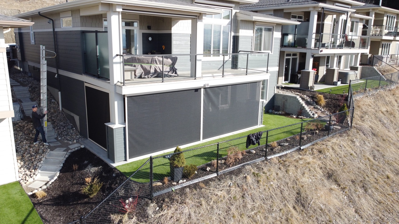 An aerial view of a row of new hillside homes with screens on the lower patios.