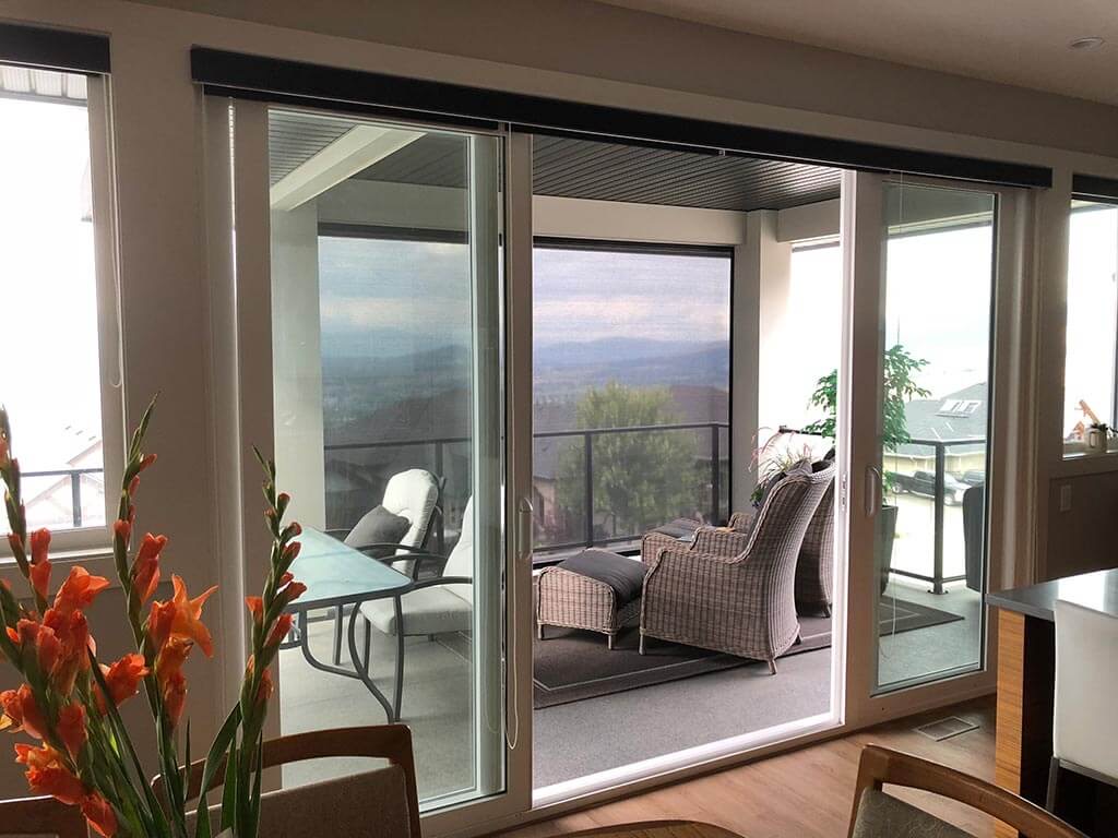 A sitting area opening onto a covered deck with a retractable screen and a view down to the lake.