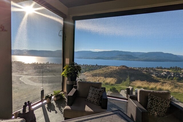 A covered patio looking out over Okanagan Lake, with a screen half lowered against the sun.