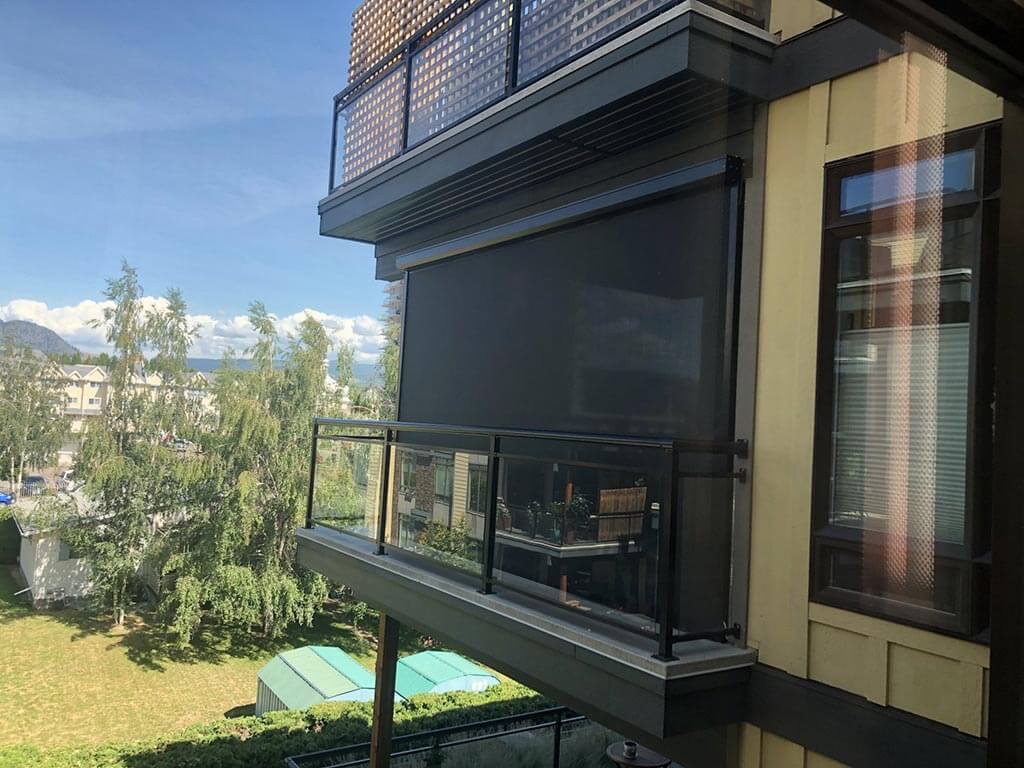 Dark retractable screens lowered around a covered balcony.