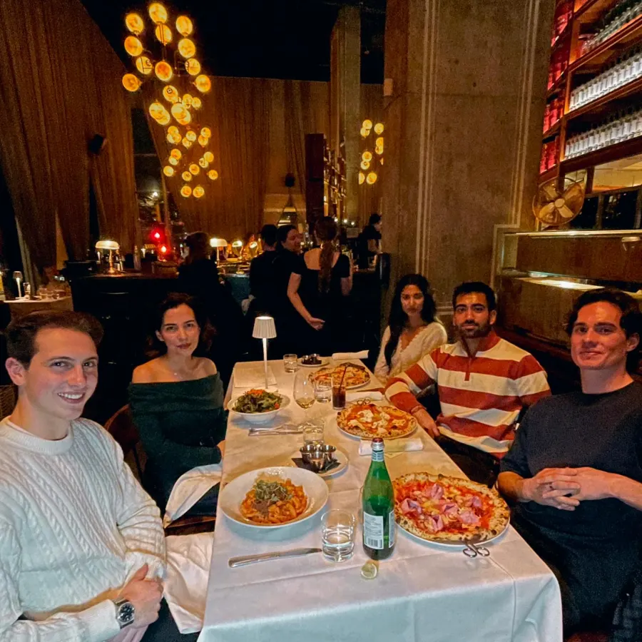 Five founders sharing pizza at a candlelit restaurant table in Vancouver